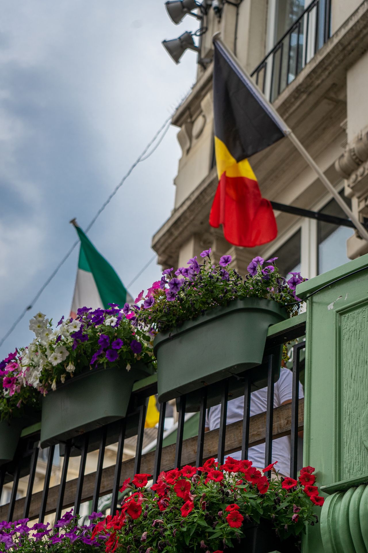 a balcony with flower boxes and a flag in the background